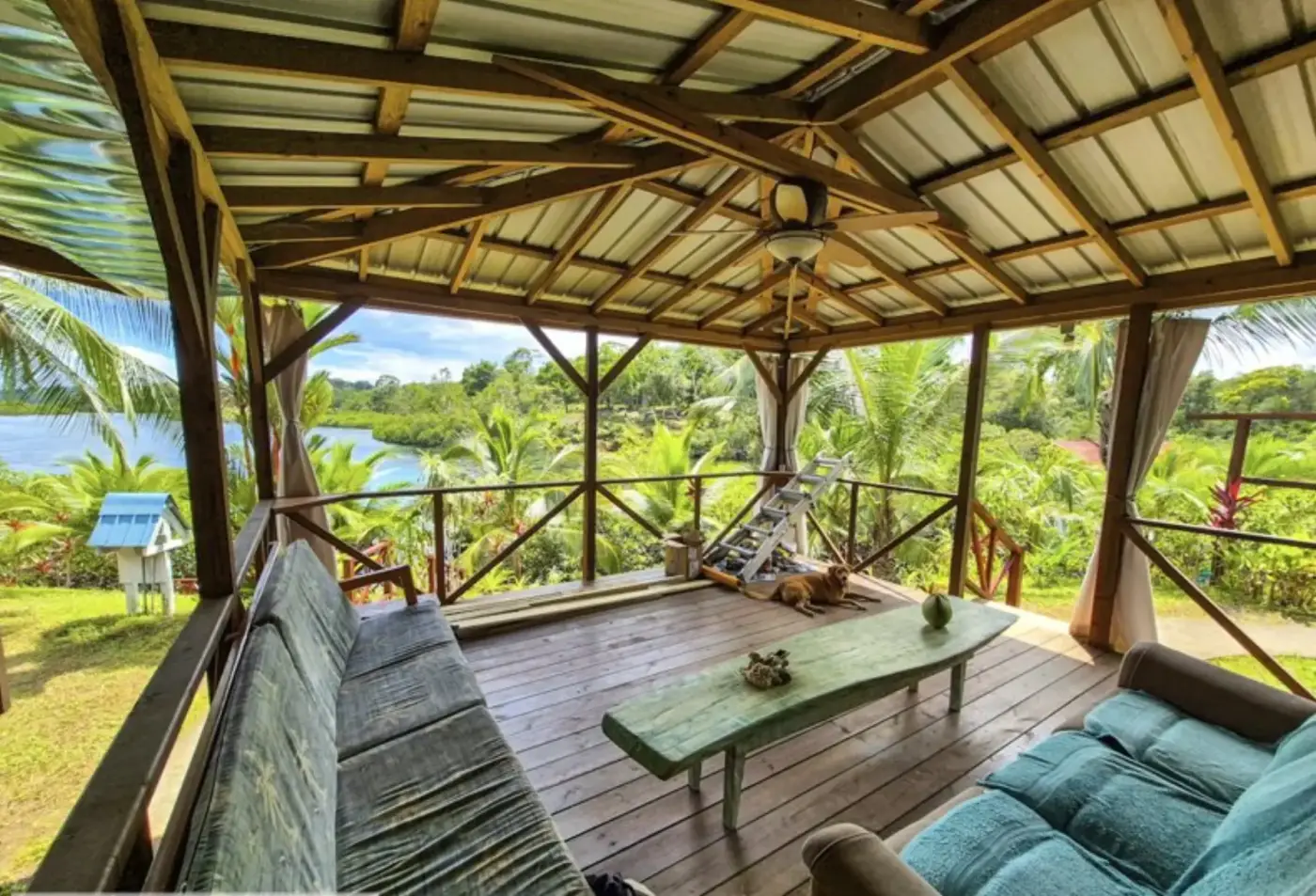 A covered deck overlooking the water, with the family dog resting in the afternoon light
